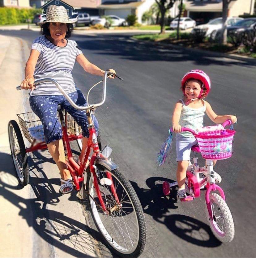 Elena riding her red tricycle beside her great-granddaughter London on her pink bicycle